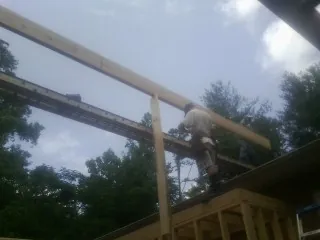Carpenter setting a ridge beam over a new addition frame — Ice Dam Removal by Roofing Brothers in Reform