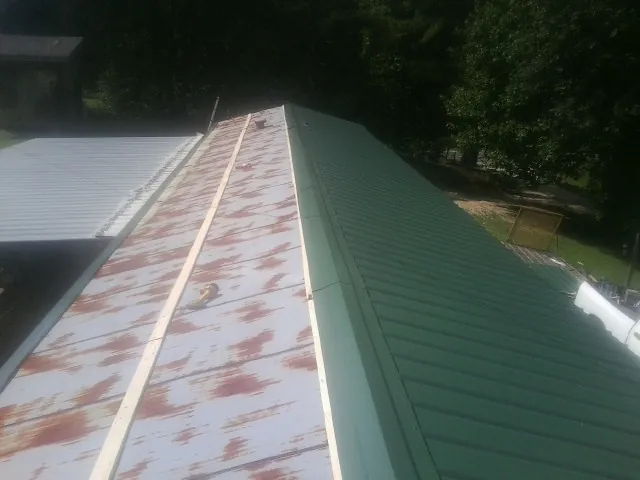 Old rusted panels beside newly installed green metal roofing — Wind Damage Roof Repair by Roofing Brothers in Reform