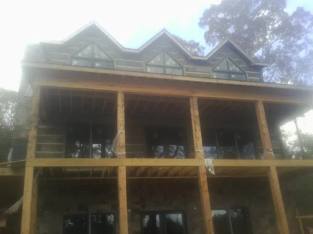 Dormers and porch framing on a large log home under construction — Roof Coating work by our crew in Reform