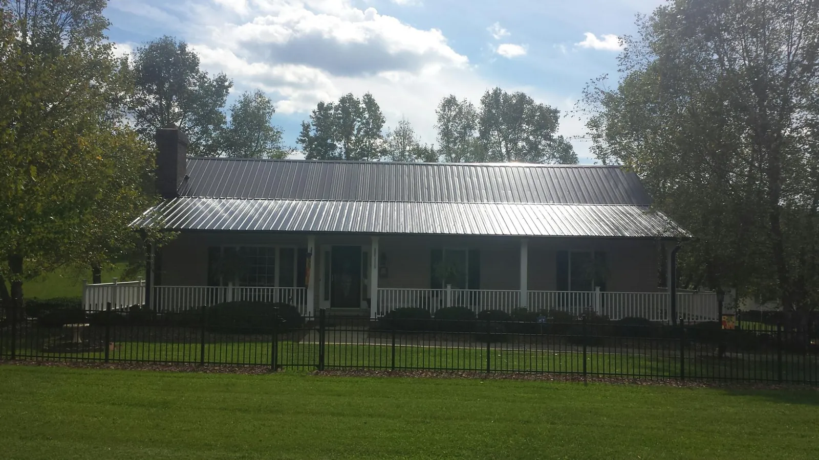 Gray metal roof on a brick ranch with a full width front porch — Gutter Guard Installation work by our crew in Reform