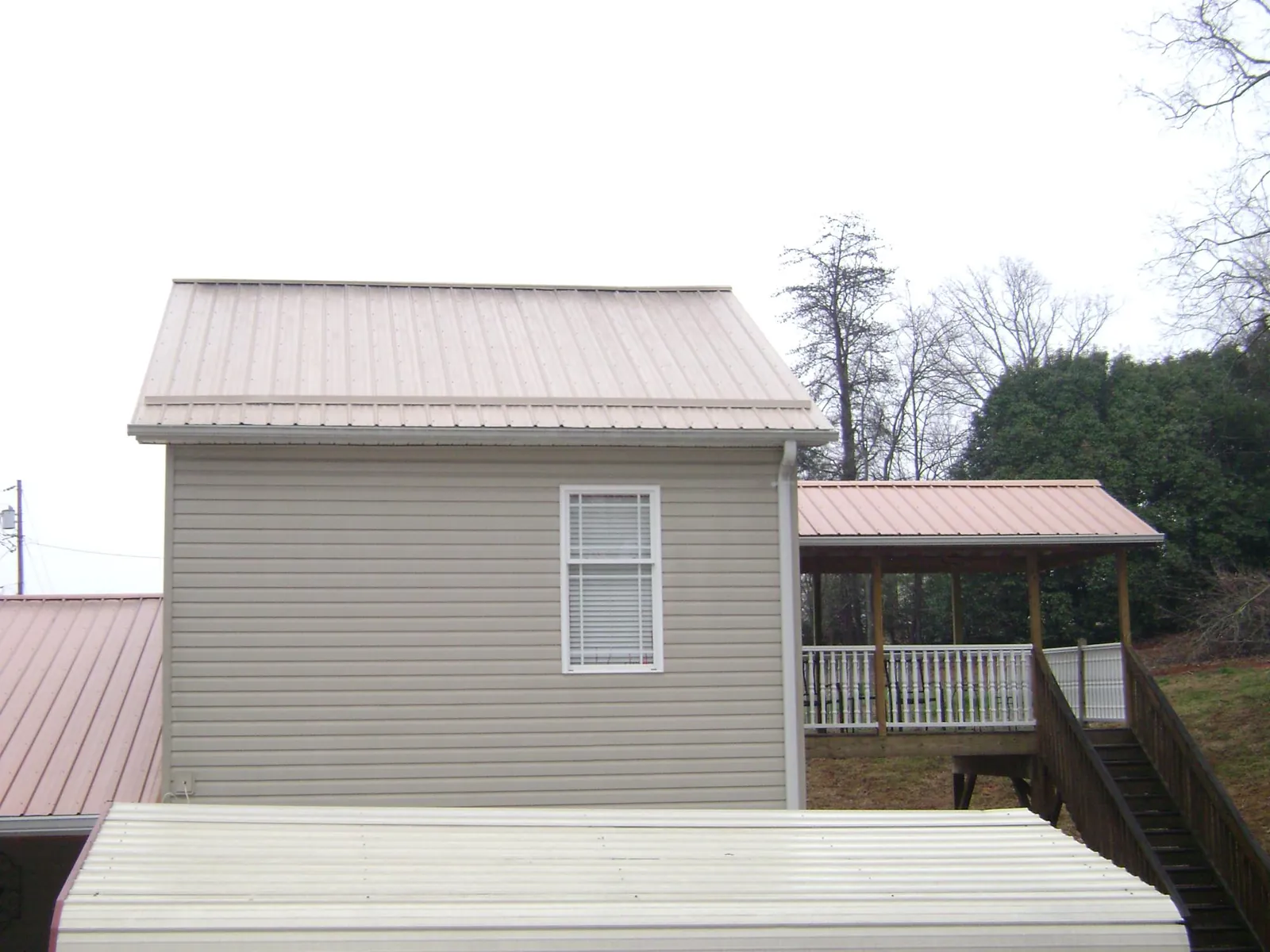 Tan metal roofs on a two story addition and attached porch, from a Roof Replacement job in Reform
