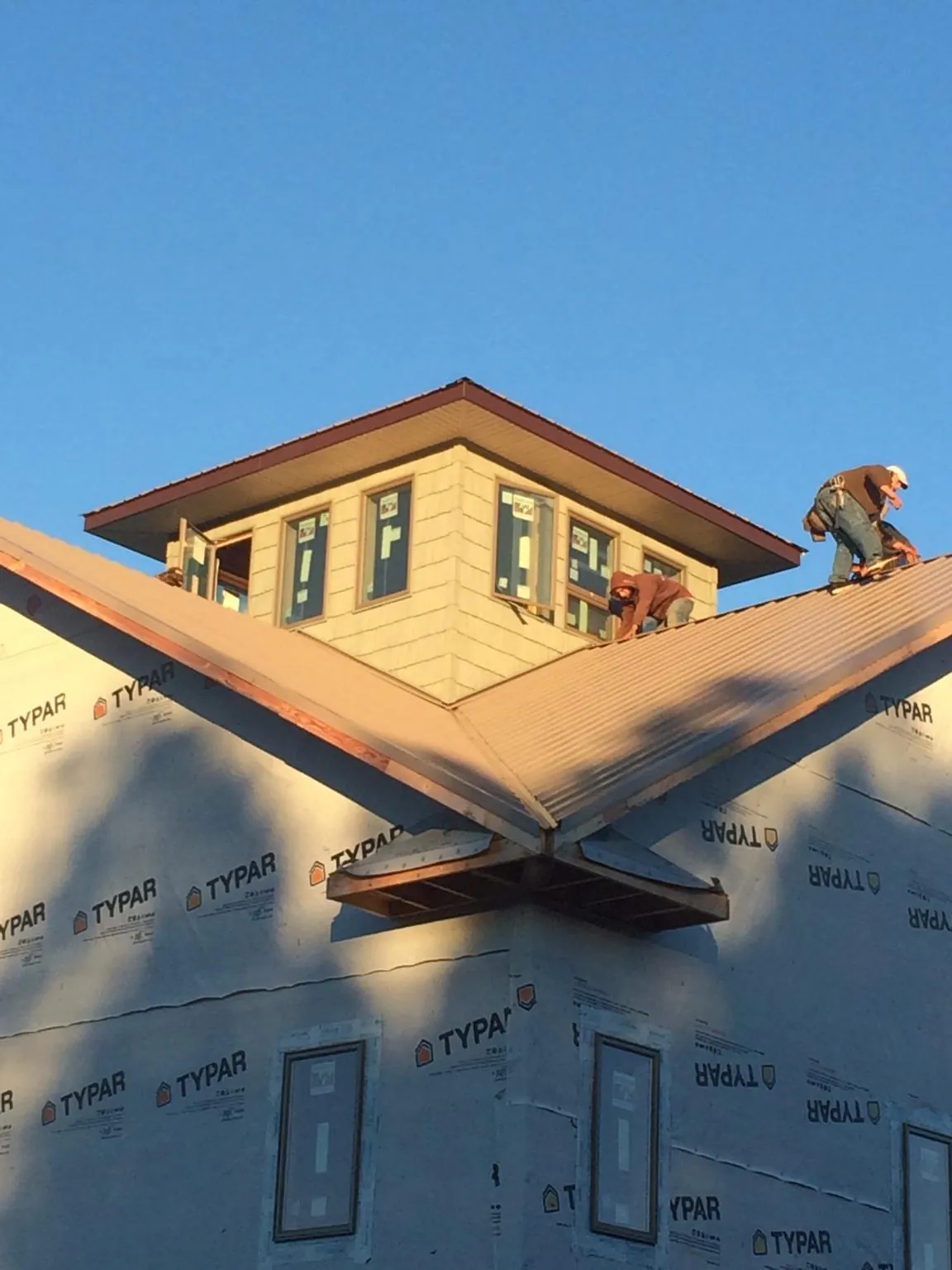 Roofers working around a rooftop cupola on a new metal roof at sunset — Roof Waterproofing in Reform by Roofing Brothers